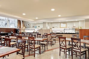 A spacious restaurant with wooden tables and chairs, a kitchen area, and various decorative items on the walls. - Hotel Best Aranea (Barcelona)