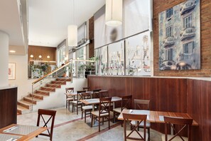 A restaurant with wooden tables and chairs, a staircase, and a mural on the wall.