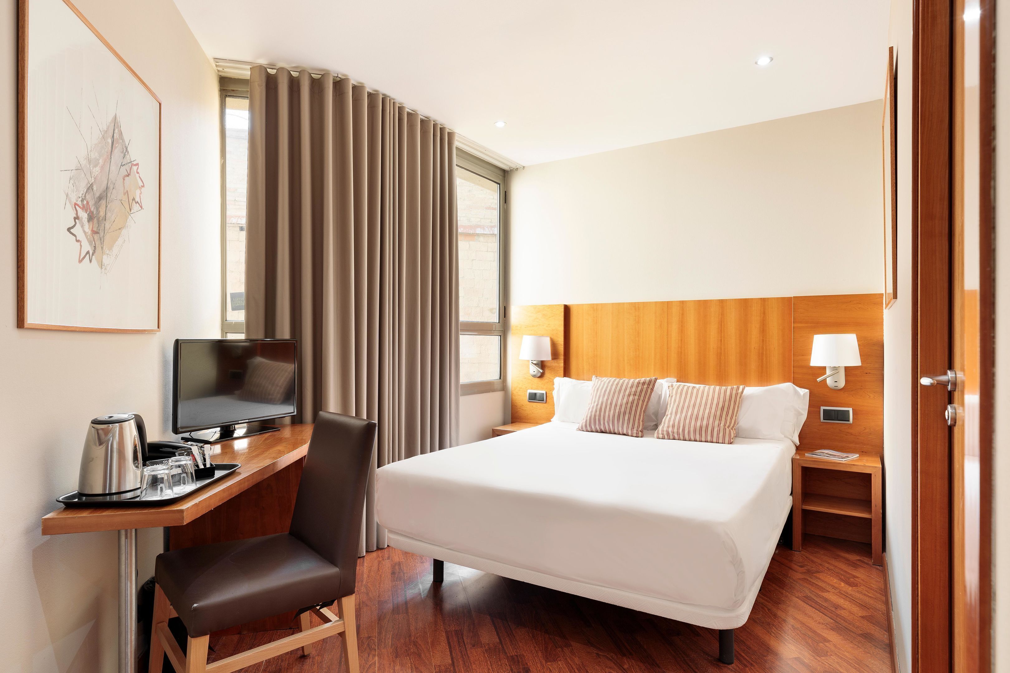 Una habitación de hotel con cama, escritorio, silla y televisor.
