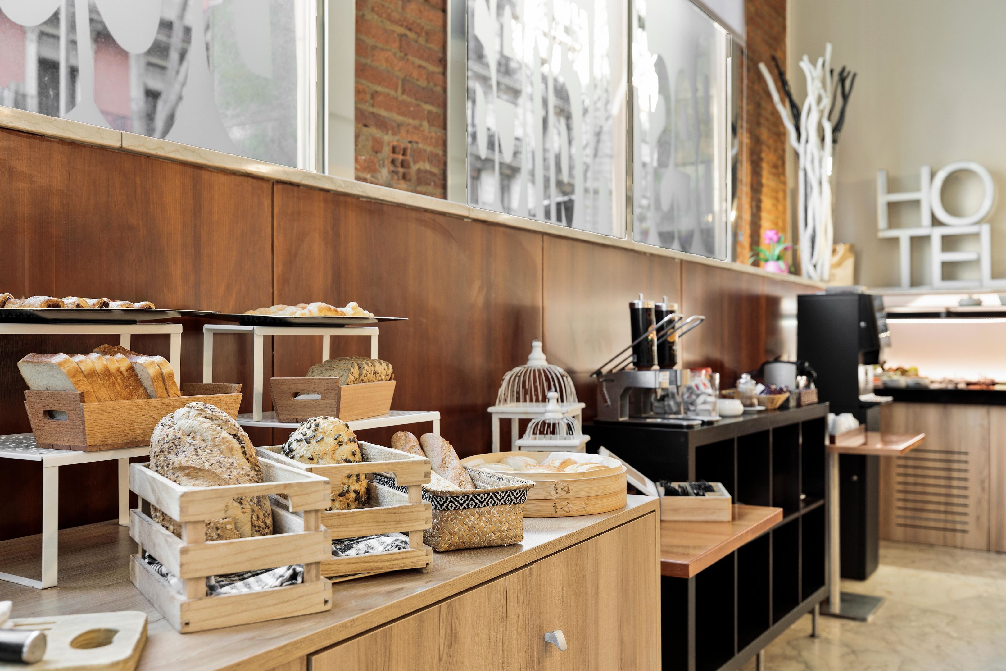 Una exhibición de panadería con diversos panes y pasteles en cajas y cestas de madera.