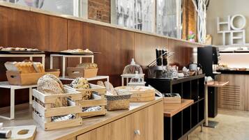 Una exhibición de panadería con diversos panes y pasteles en cajas y cestas de madera.