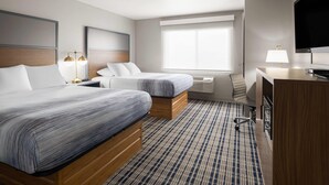 A hotel room with two beds, a desk, a TV, and a large window. - AmericInn by Wyndham Muscatine (Muscatine)