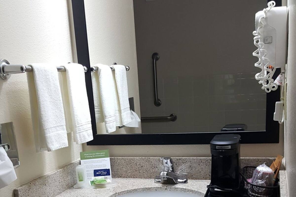 A bathroom with a sink, hand dryer, and a mirror.