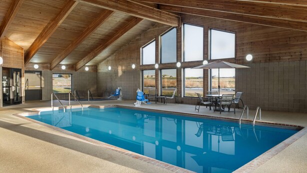 A large indoor swimming pool with a wooden ceiling and large windows. - AmericInn by Wyndham Muscatine (Muscatine)