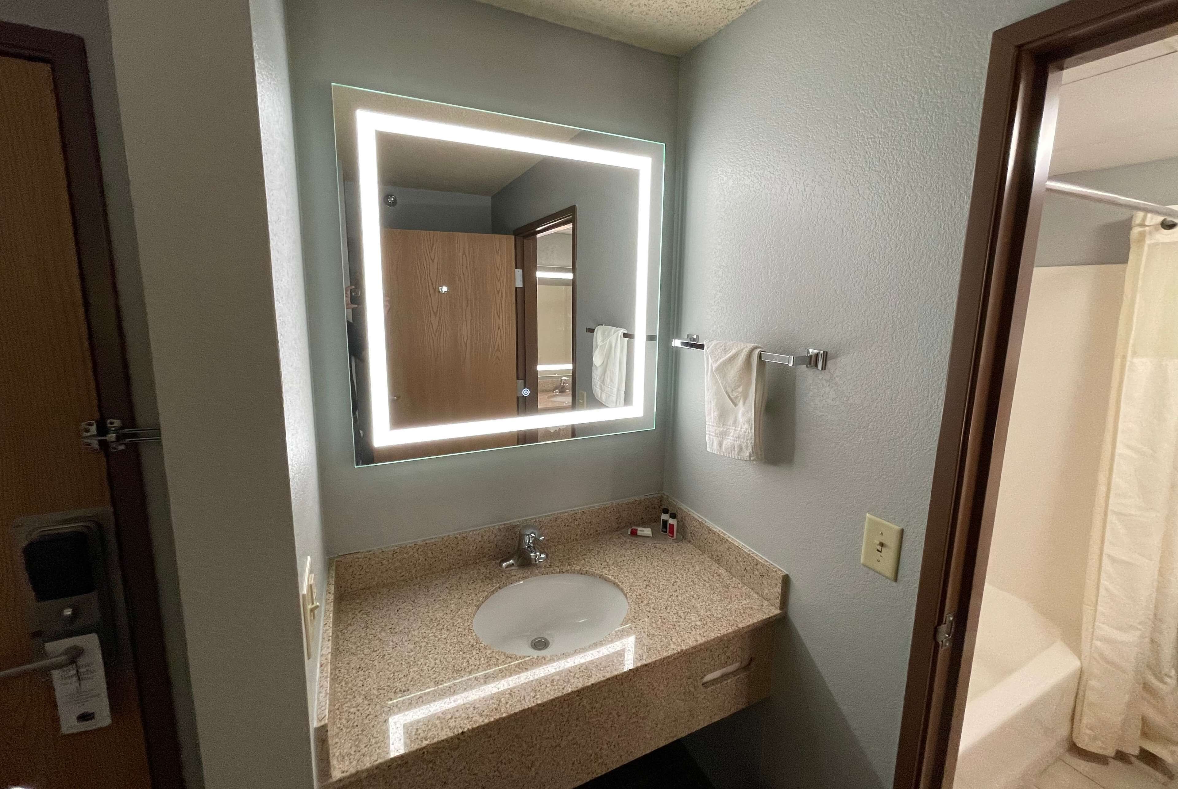 A bathroom with a sink, mirror, and towel rack.
