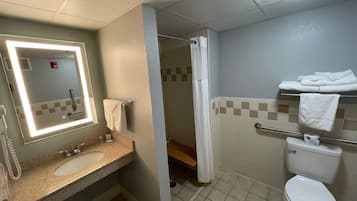 A bathroom with a sink, mirror, toilet, and shower.