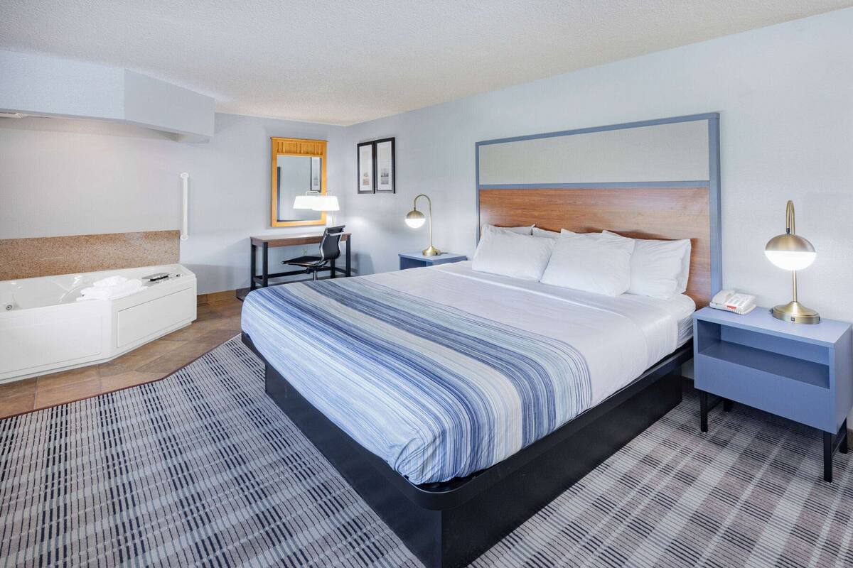 A hotel room with a large bed, a desk, a chair, a sofa, and a bathroom.