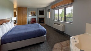 A hotel room with a bed, a chair, a fireplace, a window with a view, and a bathtub. - Black Beach Inn by GrandStay (Silver Bay)