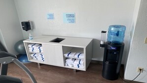 A fitness center area with a water dispenser, towels, and exercise equipment. - Holiday Inn Express & Suites Enterprise by IHG (Enterprise)