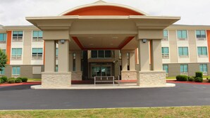 A multi-story hotel entrance with a covered walkway, stone pillars, and a red roof. - Holiday Inn Express & Suites Enterprise by IHG (Enterprise)