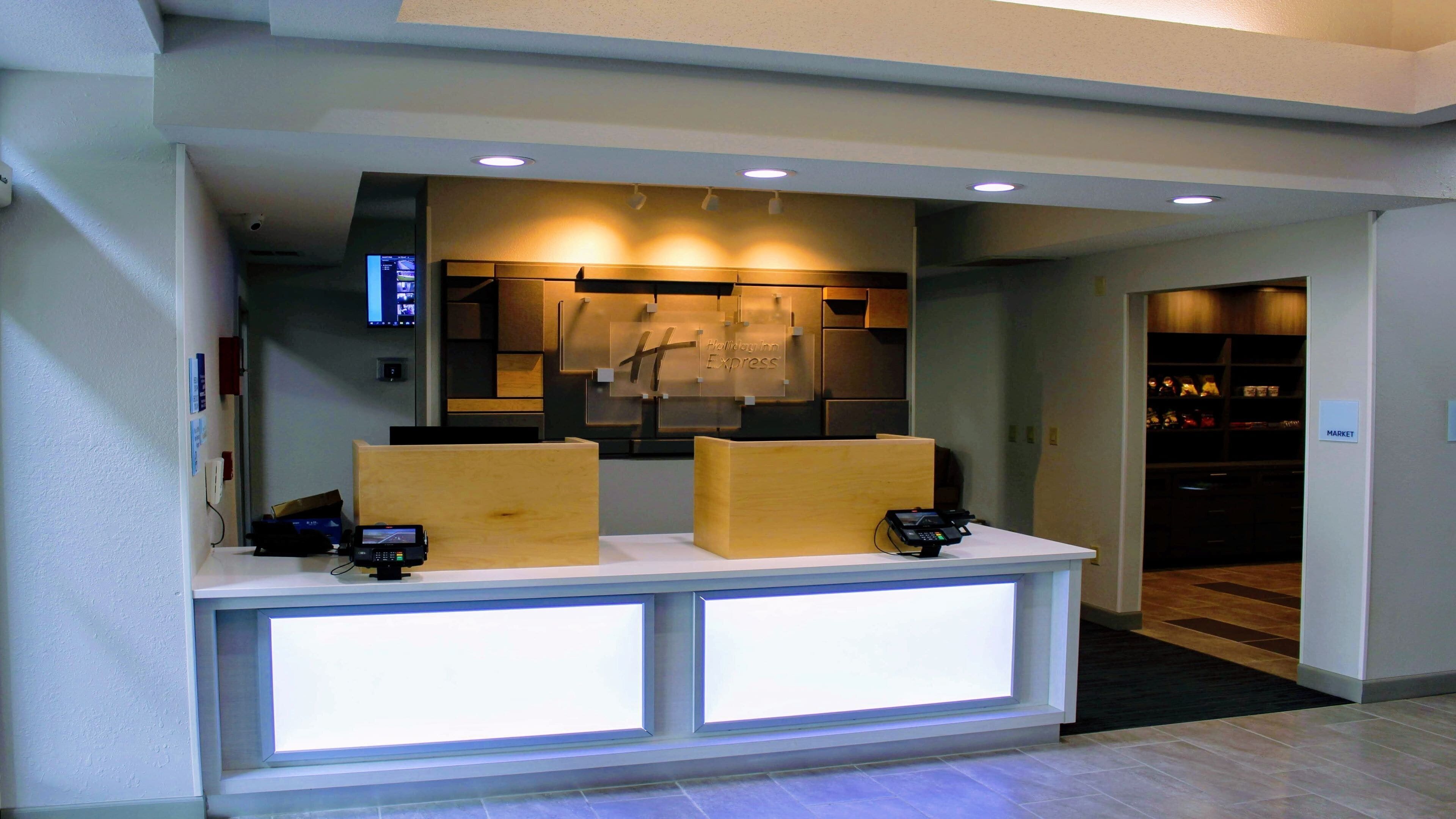 A reception desk with a digital display, a cash register, and a sign for the Holiday Inn Express.