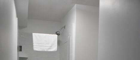 A bathroom with a shower, toilet, and a towel rack.