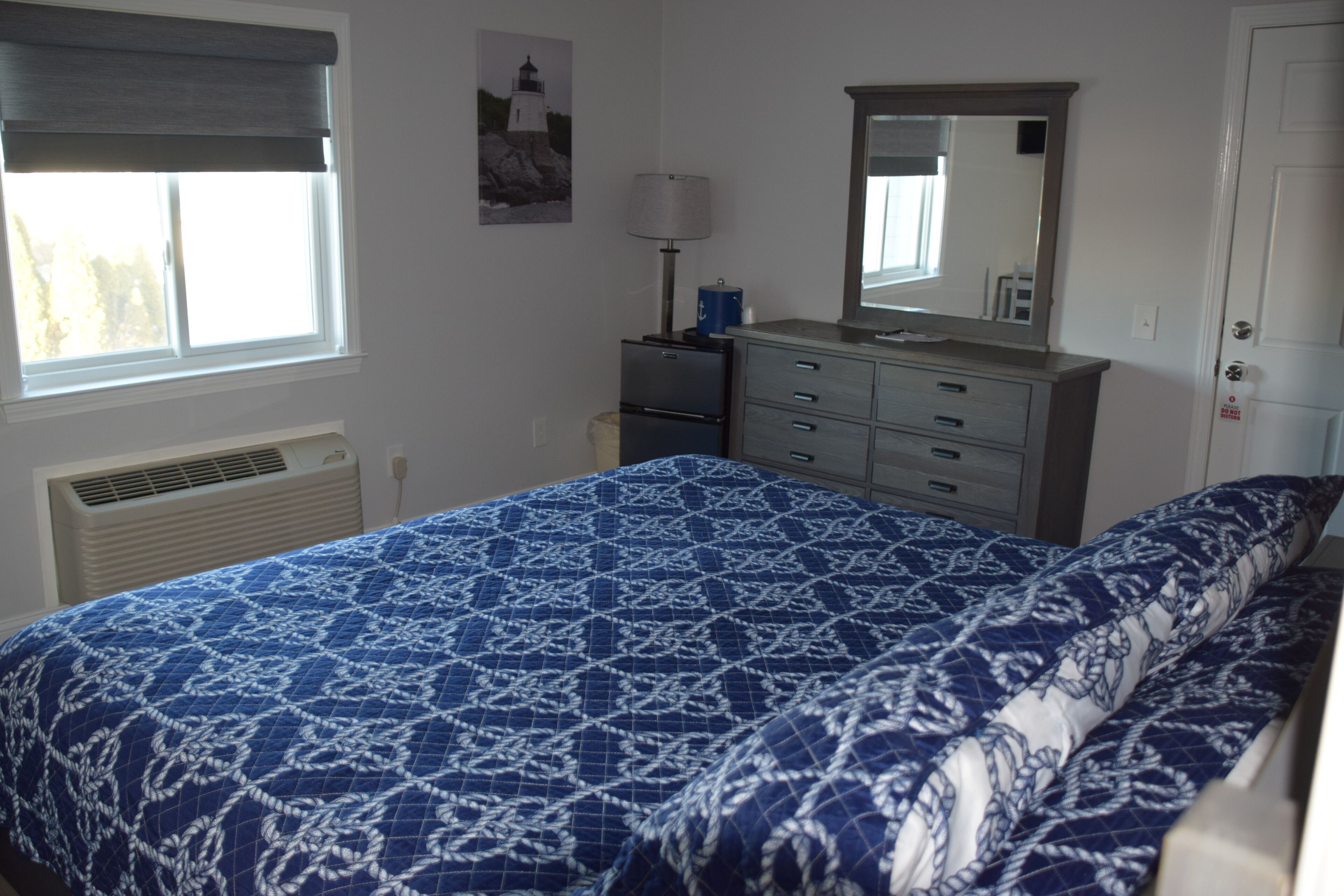 A bedroom with a bed, a dresser, a mirror, a window, and a heater.