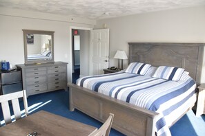 A bedroom with a bed, dresser, mirror, and a desk with a chair.