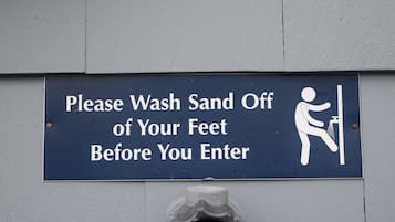 A sign instructing to wash sand off feet before entering.