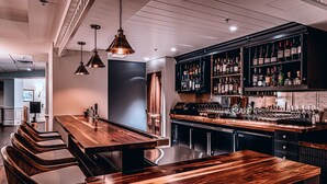 A modern kitchen with a wooden bar area, built-in wine racks, and bar stools. - The Bellmoor Inn & Spa (Rehoboth Beach)