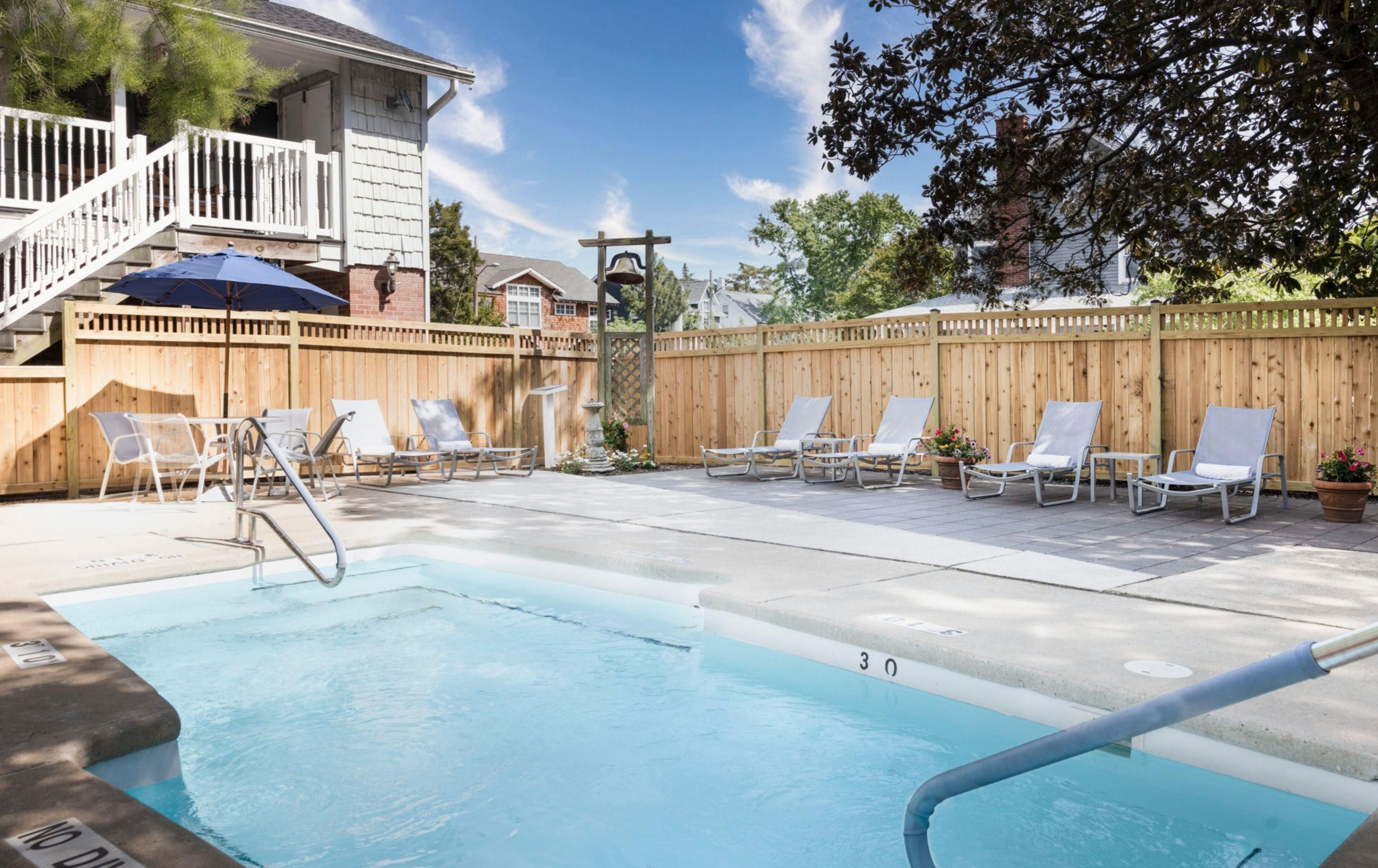 A swimming pool with lounge chairs and a wooden fence.