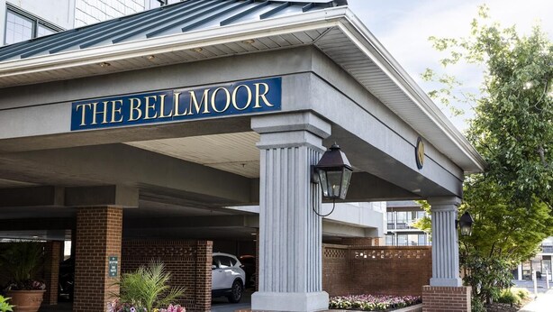 The Bellmoor hotel entrance with a covered parking area, brick pillars, and potted plants.