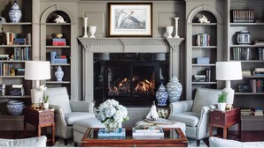 A living room with a fireplace, bookshelves, and two armchairs. - The Bellmoor Inn & Spa (Rehoboth Beach)