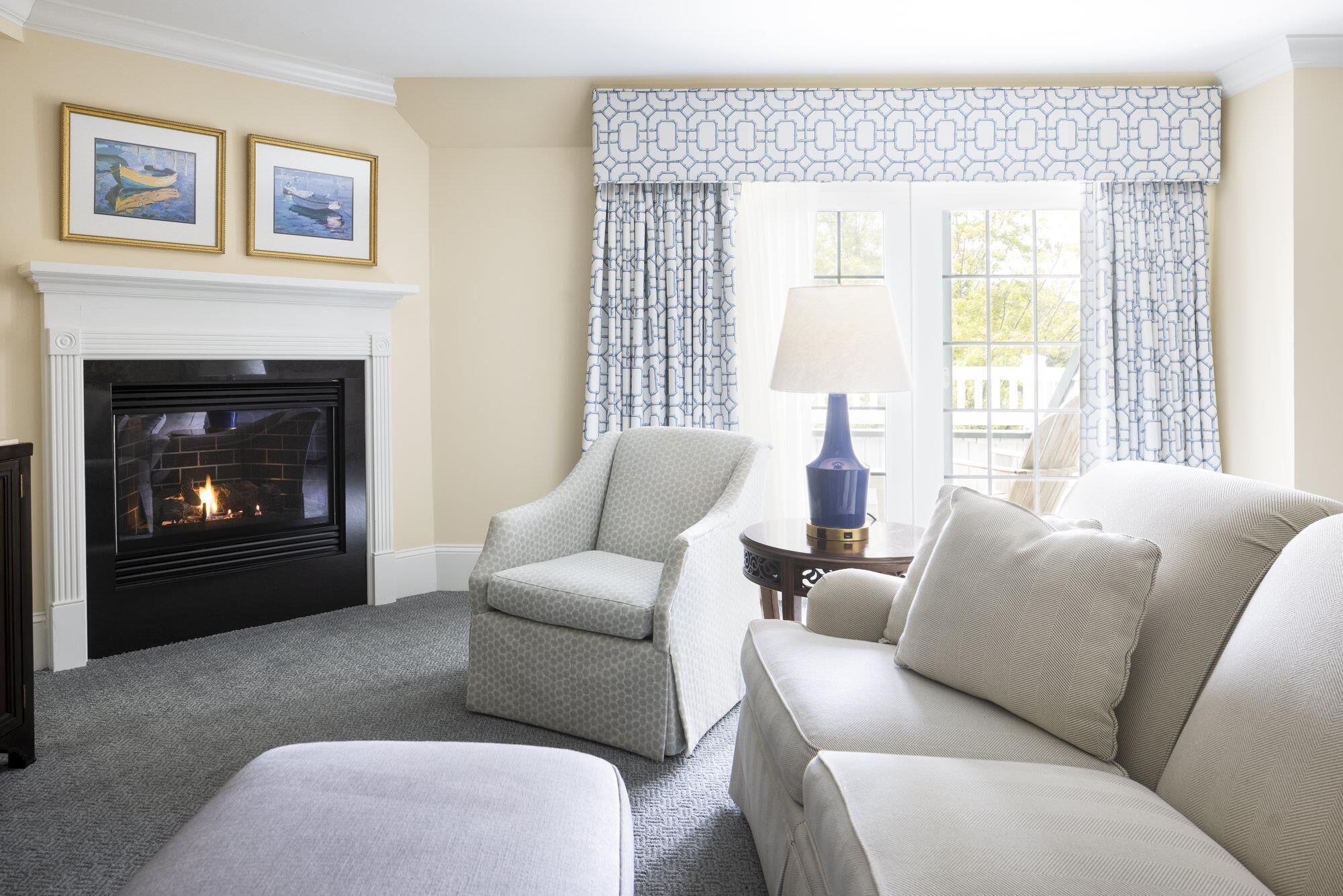 A living room with a fireplace, two armchairs, a sofa, and a table with a lamp.