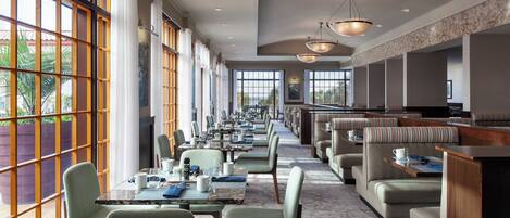 A spacious dining area with high ceilings, large windows, and modern lighting fixtures.