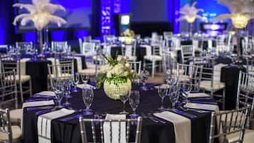 A formal dining room with round tables, white chairs, and elegant floral centerpieces.