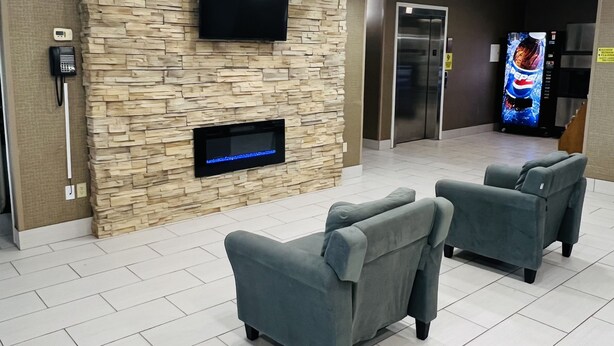Eine Lobby mit Steinwand, zwei Sofas, einem Flachbildfernseher, einem Telefon und einem Verkaufsautomaten.