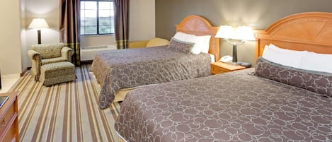 A hotel room with two beds, a chair, a desk, and a window with curtains.