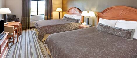 A hotel room with two beds, a desk, a TV, and a window with curtains.