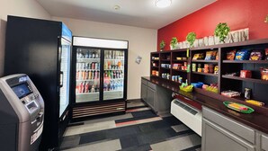 A small kitchenette with a refrigerator, an ATM, and a snack shelf.
