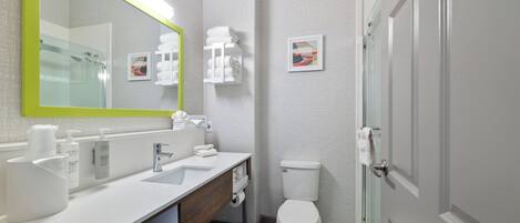 Un baño moderno con lavamanos, espejo e inodoro blancos.