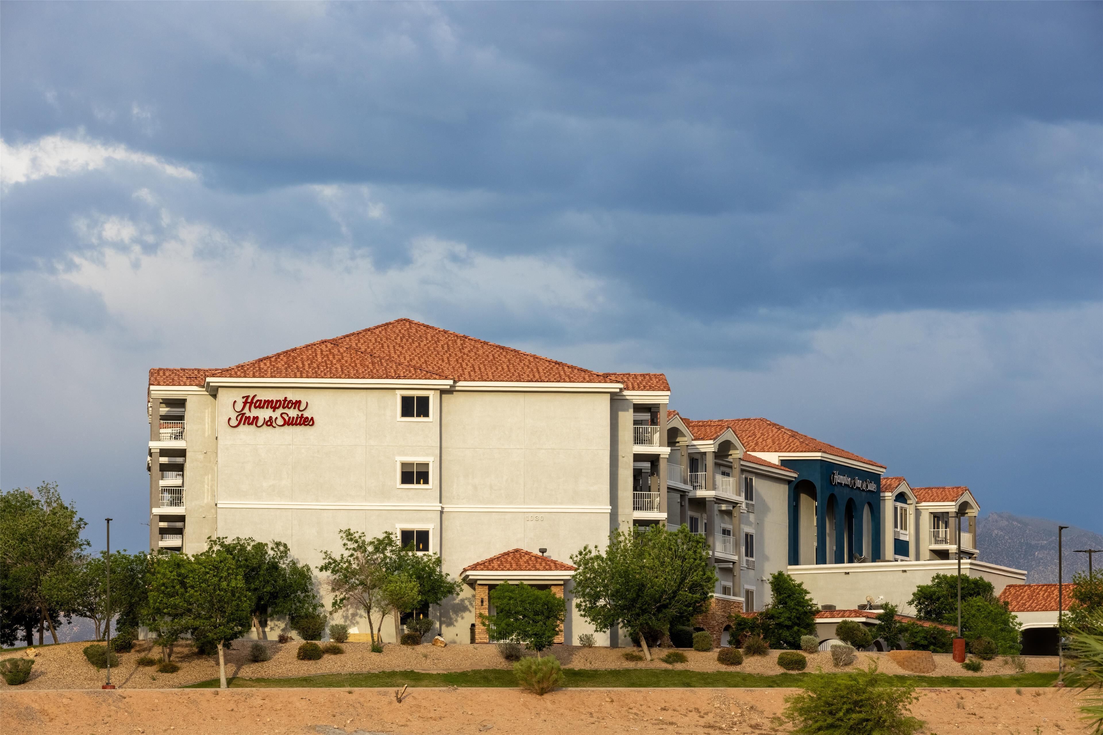 Un hotel con techo de tejas rojas, varios balcones y un cartel que dice 'Hampton Inn & Suites'.