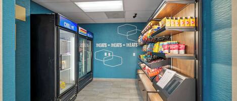 A snack bar with a refrigerated display and shelves stocked with snacks.