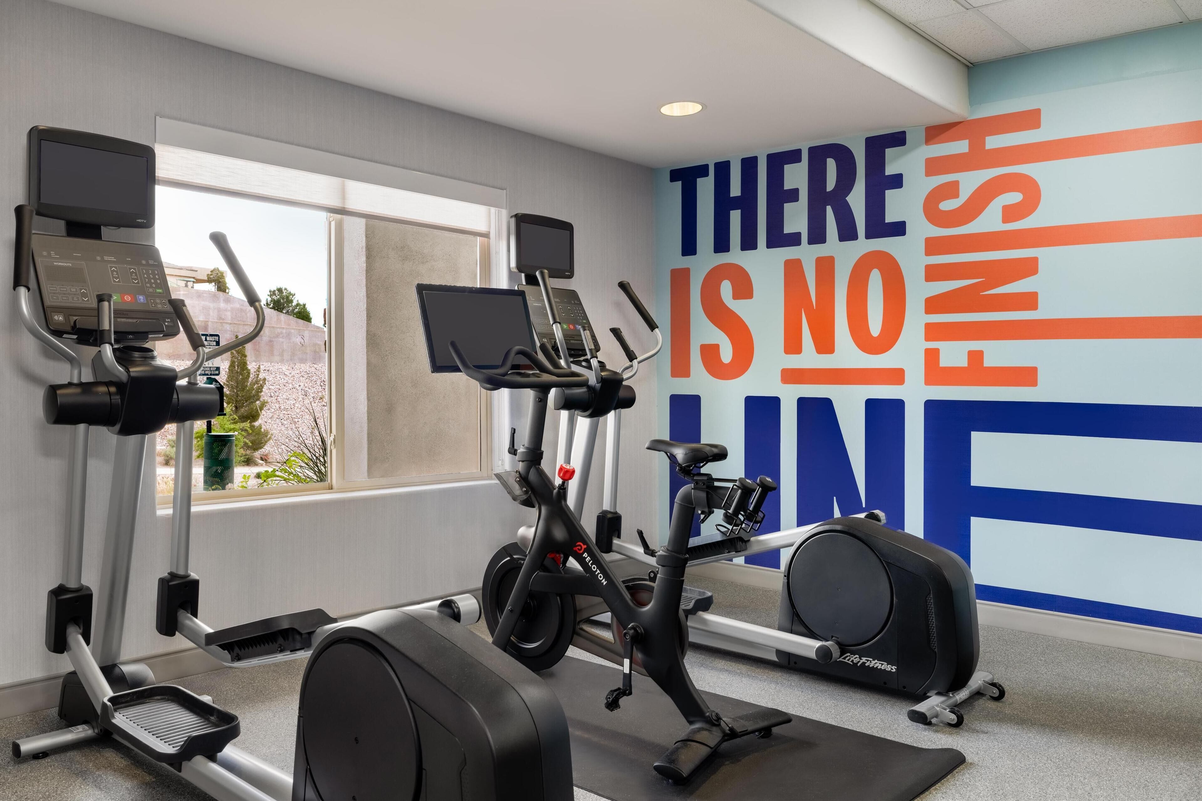 A gym with exercise equipment, a motivational wall, and a window with a view.