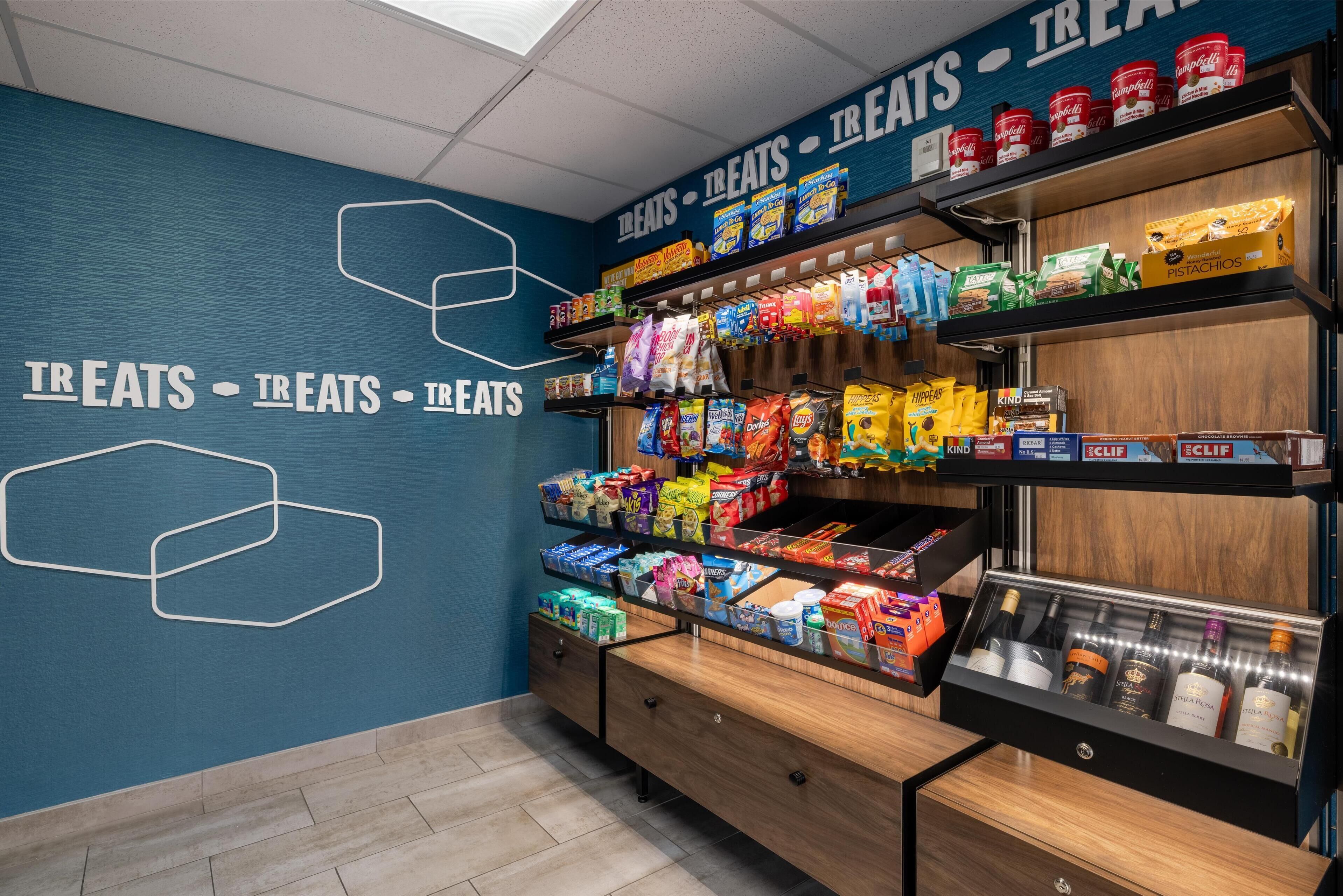 Esposizione di snack e bevande in un negozio, con scaffali multipli e un reparto refrigerato.