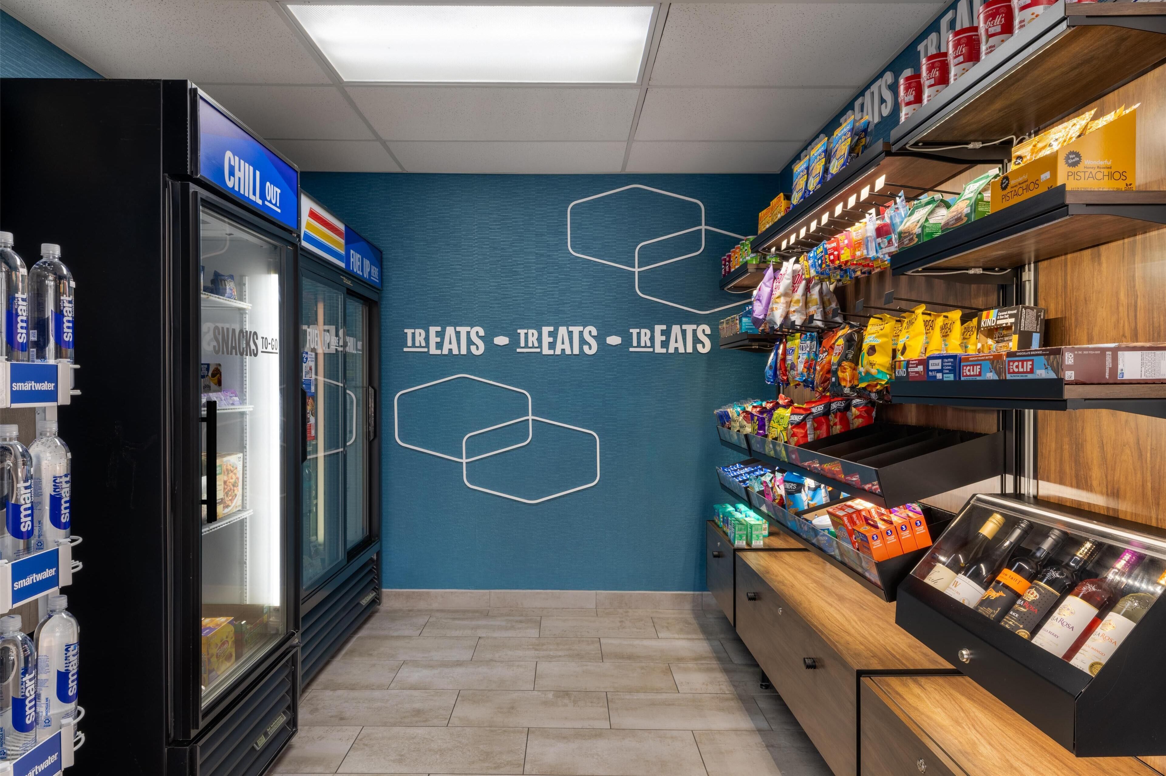 A snack and beverage area with a 'CHILL OUT' sign, a refrigerator, shelves stocked with snacks, and a display case with bottled beverages.