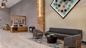 A lobby with a reception desk, seating area, and a wall-mounted light fixture.