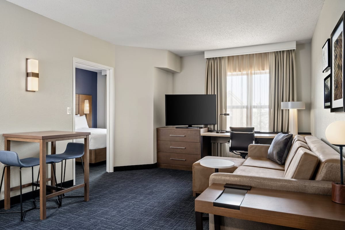 A hotel room with a desk, a sofa, a television, and a bed.