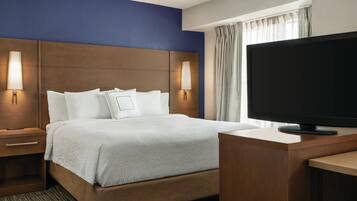 A hotel room with a large bed, a TV on a wooden stand, and two bedside lamps.