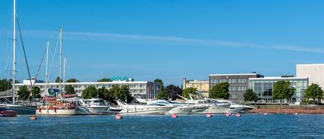 A marina with multiple boats docked, a building with a sign, and a clear blue sky.