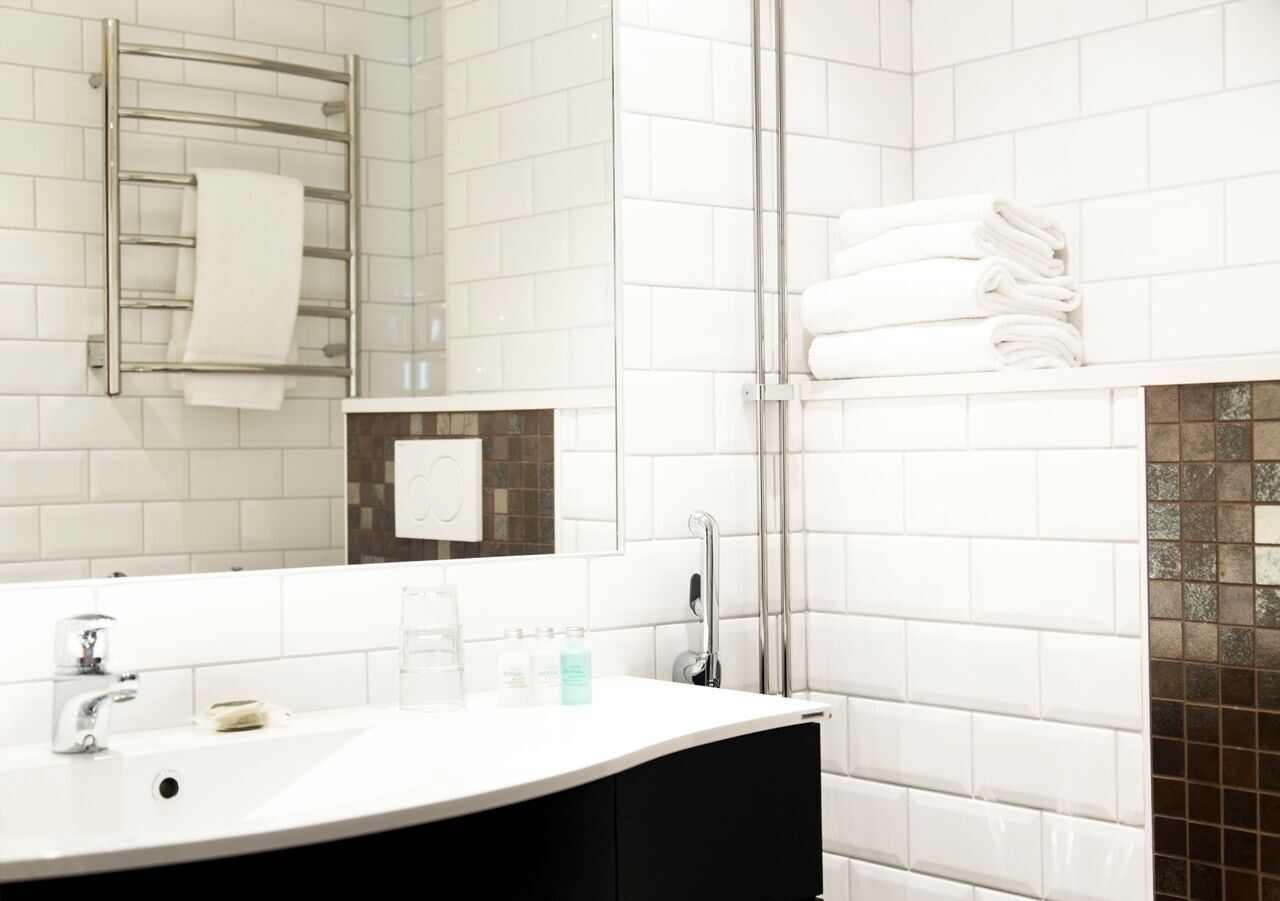 Een moderne badkamer met een witte wastafel, een spiegel en een douchecabine van glas.