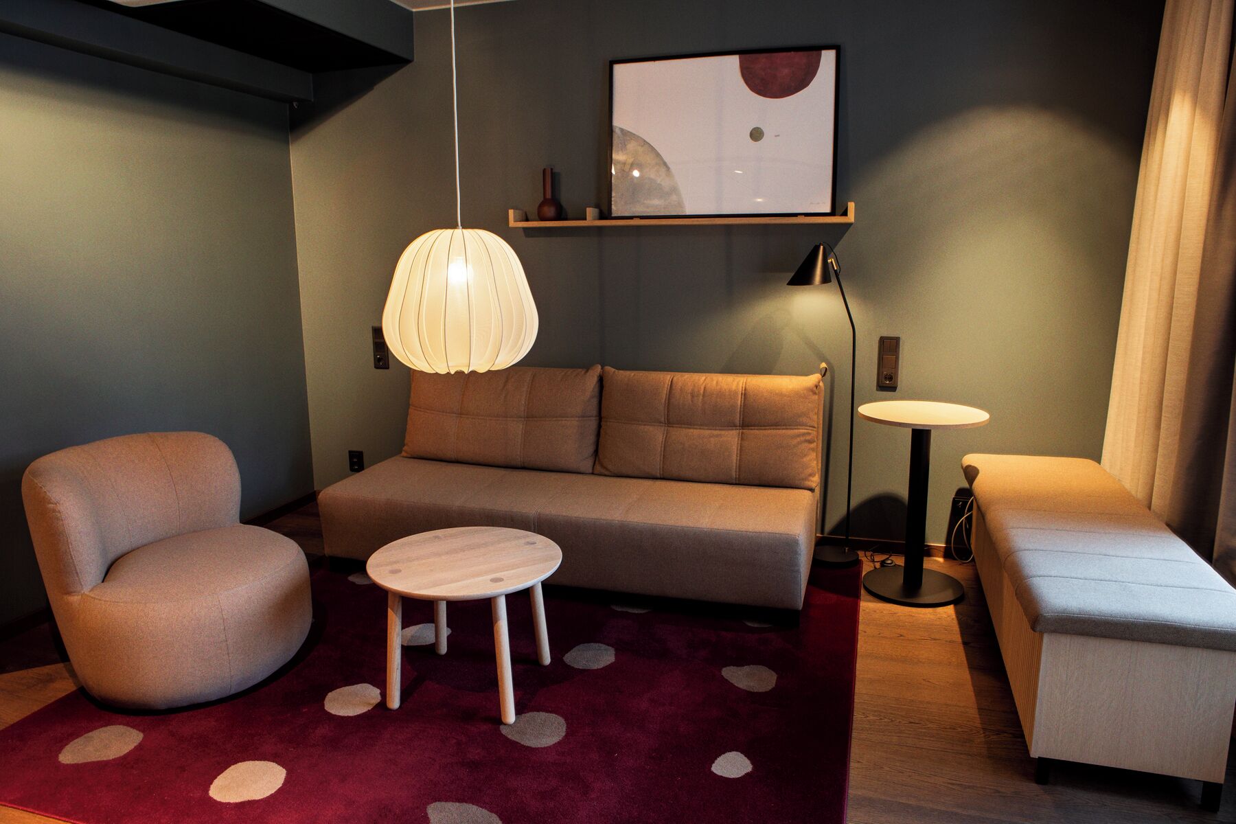 Una sala moderna con un sofá, dos sillones, una mesita redonda y una lámpara de pie.
