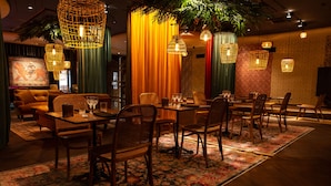 A dining area with tables and chairs, warm lighting, and a decorative plant. - Hotell Arkipelag (Mariehamn)