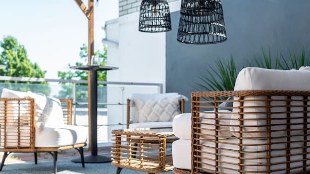 Wicker furniture with cushions, a round table, and hanging wicker lamps on an outdoor balcony. - Hotell Arkipelag (Mariehamn)