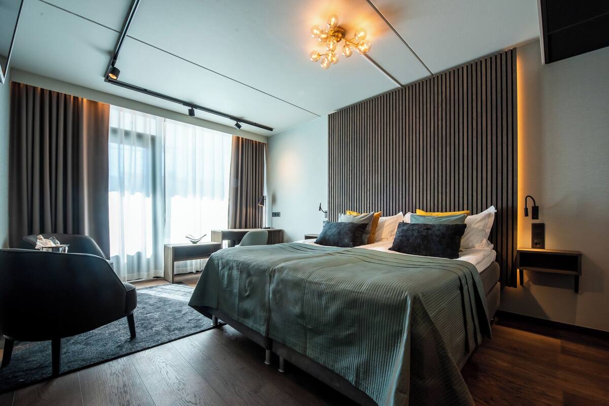 Moderni hotellihuone, jossa on suuri sänky, työpöytä ja tuoli.