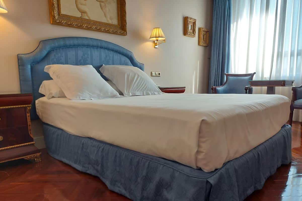 Une chambre d’hôtel avec un grand lit, une table de chevet en bois, un bureau et une chaise.