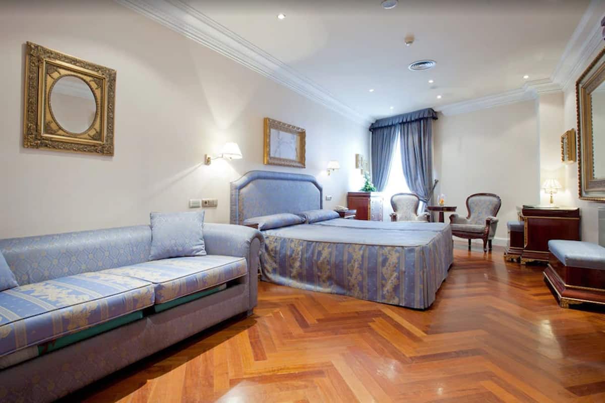 Une chambre d’hôtel avec un canapé, un lit, un bureau et une chaise.