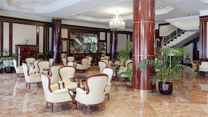 A spacious lobby with marble flooring, elegant chairs, a grand staircase, and a large chandelier. - Alameda Palace (Salamanca)