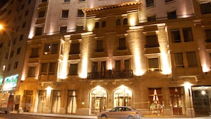 A multi-story hotel with illuminated columns, large arched entrances, and balconies. - Alameda Palace (Salamanca)
