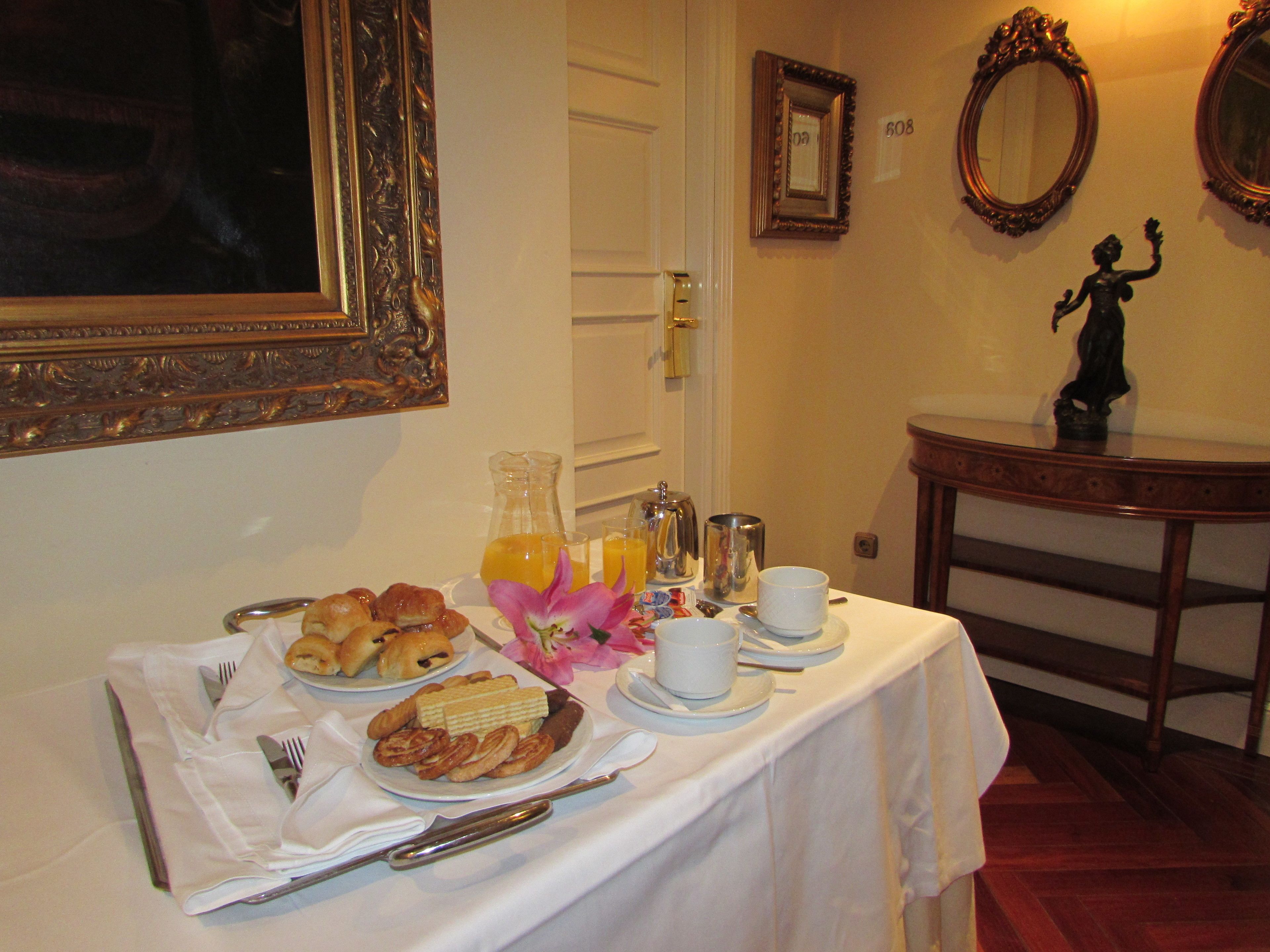 Una mesa de desayuno con cruasanes, pasteles, jugo y café.